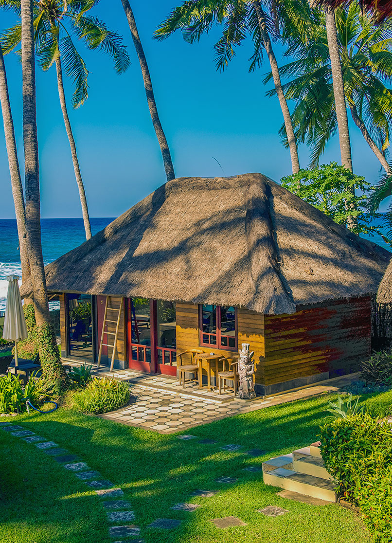 Kleiner Bungalow zwischen Palmen am Meer.