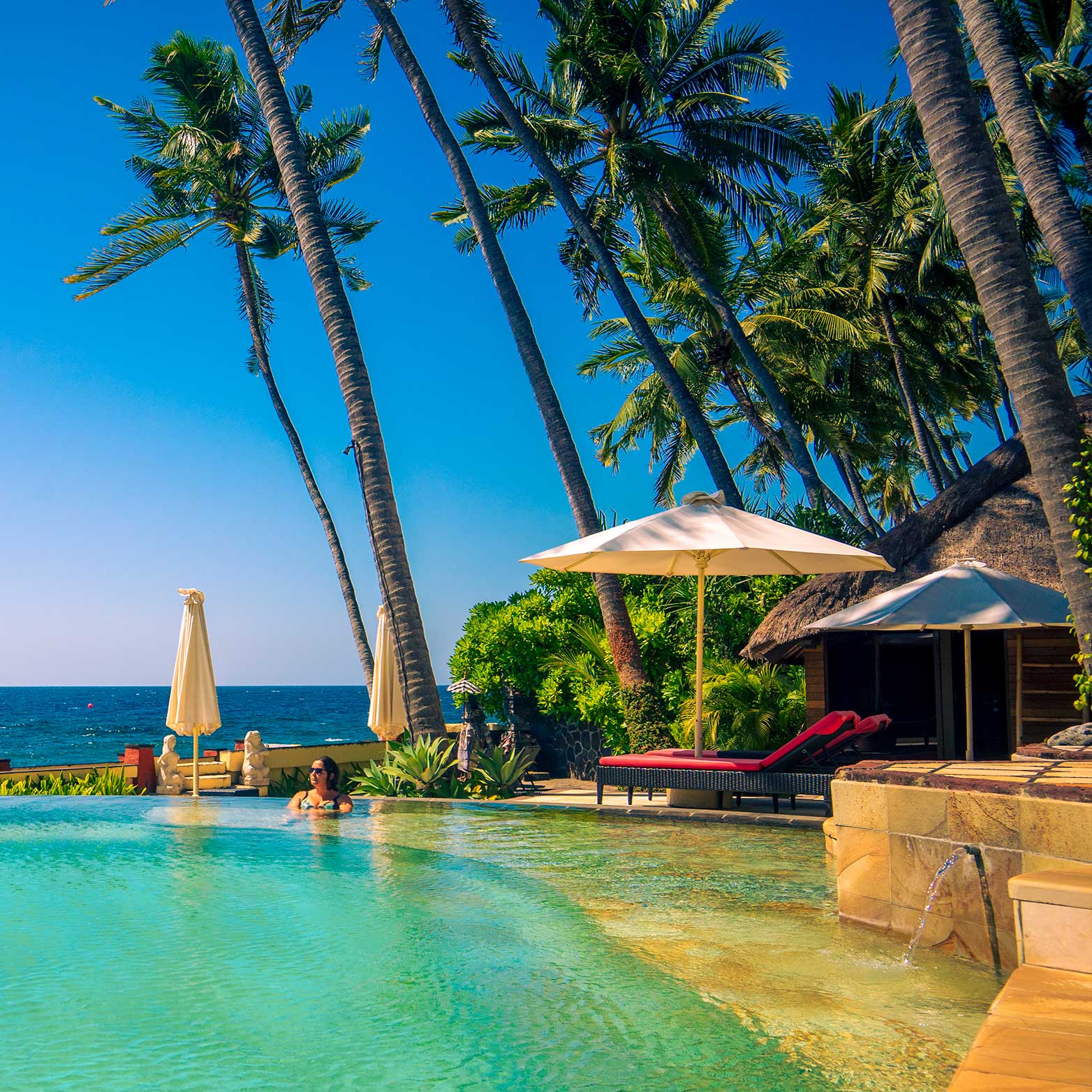 Infinity Pool mit Liegen direkt am Meer.